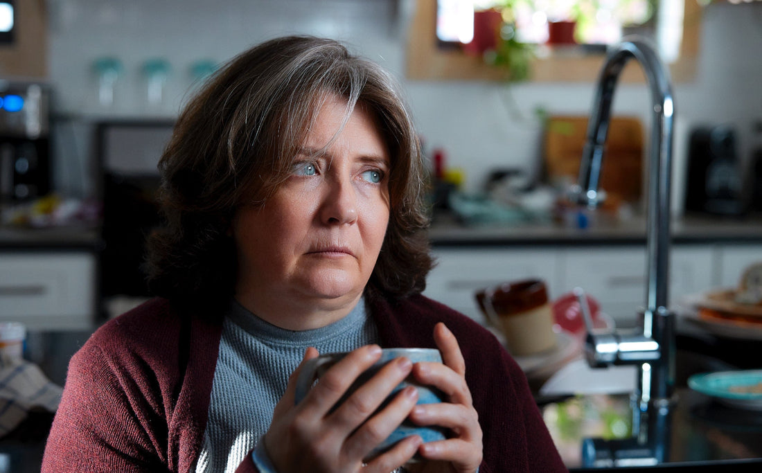 Depressed woman holding a cup of coffee and wearing a red sweater with grey shirt